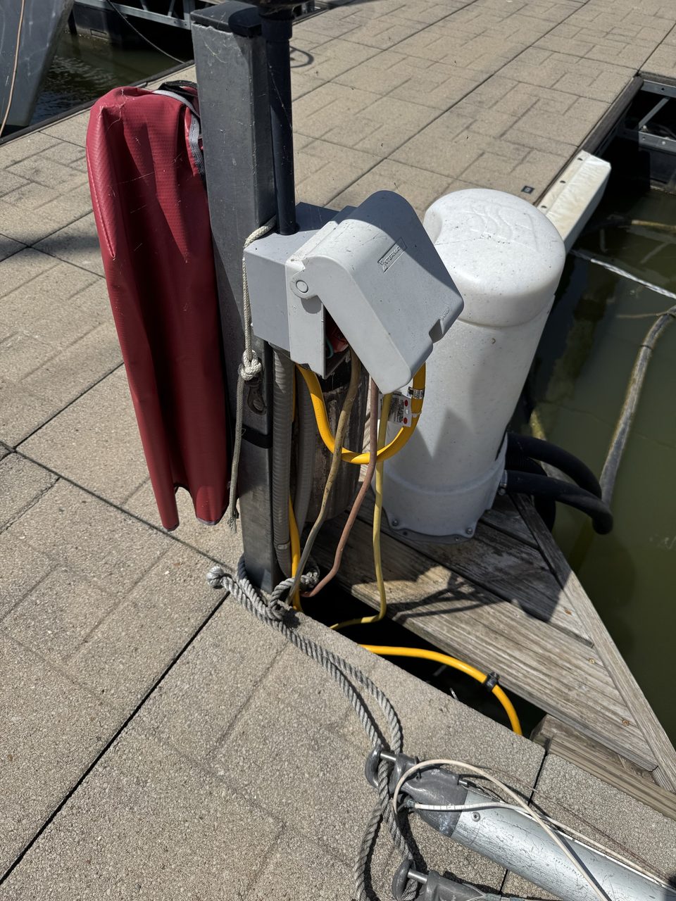 The dock pedestal with its weatherproof outlet box, the yellow shore-power cord led down and secured